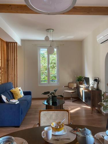 een woonkamer met een blauwe bank en een tafel bij La Maison de Jeanne in Narbonne