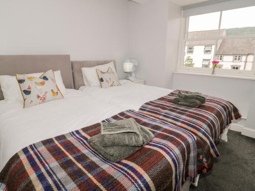 a bedroom with a bed with a blanket and a window at Hand Apartment in Llanrwst
