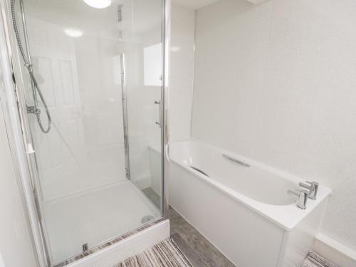 a white bathroom with a shower and a sink at Hand Apartment in Llanrwst