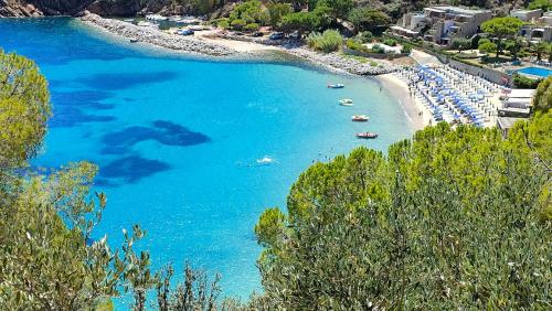 a beach with umbrellas and boats in the water at Isola del Giglio casa Nico e casa Camilla Monticello Giglio Porto in Isola del Giglio