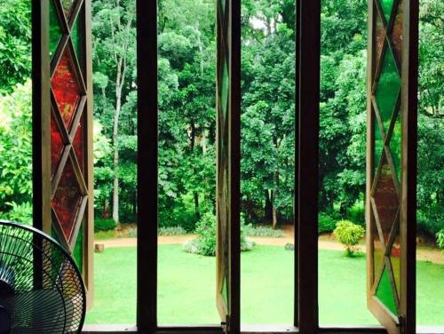 a window with a view of a park seen through it at Elpitiya Walauwa Heritage Home in Gampola