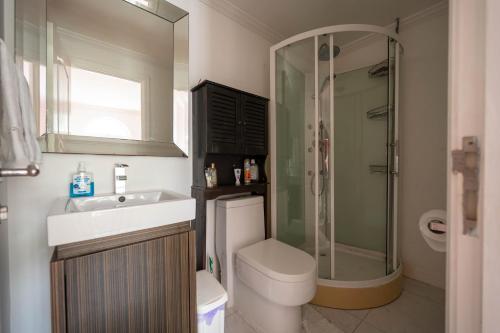 uma casa de banho com um chuveiro, um WC e um lavatório. em JAG Guesthouse- Little Bay Country Club em Negril