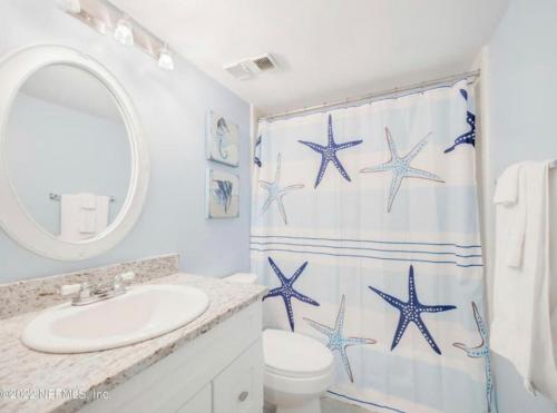 uma casa de banho com um lavatório e uma cortina de chuveiro com estrela-do-mar azul em Oasis 21 Oceanfront with Pool em Saint Augustine