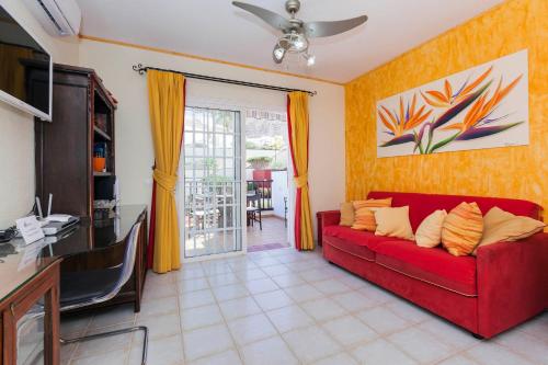a living room with a red couch and a table at Penthouse El Mirador Los Cristianos Tenerife - VV in Los Cristianos