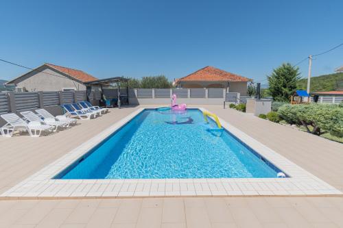a swimming pool with a girl in the middle of it at Spacious villa for 10 with a big private pool in Trilj