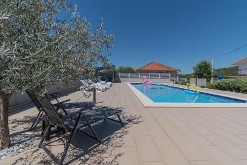 a patio with chairs and a swimming pool at Spacious villa for 10 with a big private pool in Trilj