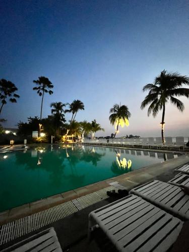 a swimming pool with palm trees and the ocean at night at The Regency Tanjung Tuan Beach Resort Port Dickson in Port Dickson