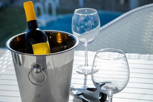 4Ever Palace - Design & Nature في ألكاسير دو سال: دلو من النبيذ يجلس على طاولة مع أكواب النبيذ