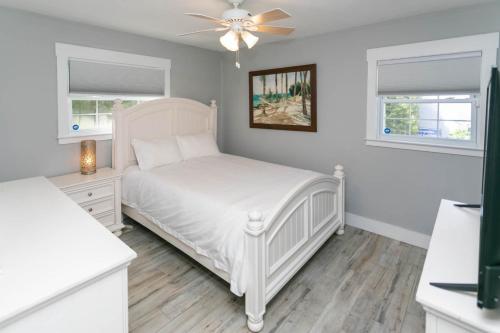 a white bedroom with a bed and a ceiling fan at Captains Quarters Island location Hot tub One Level in St. Augustine