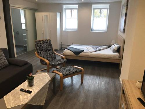 ein kleines Wohnzimmer mit einem Bett und einem Stuhl in der Unterkunft Modernes 1-Zimmer-Apartment im Herzen Oberkochens in Oberkochen