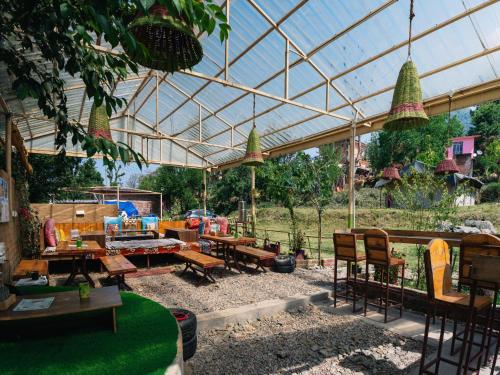 a patio with tables and chairs under a glass roof at The Bunker Bir in Bīr