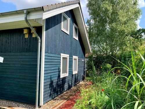 ein blaues Haus mit offener Tür in einem Hof in der Unterkunft Lovely holiday home in D mmer near lake in Dümmer