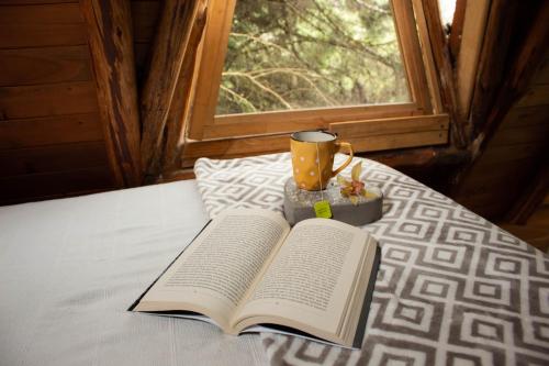 an open book sitting on a bed with a cup at Glamping con jacuzzi cerca a Medellin in Guarne