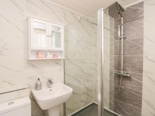 a white bathroom with a sink and a shower at Red Grouse Cottage in Guisborough