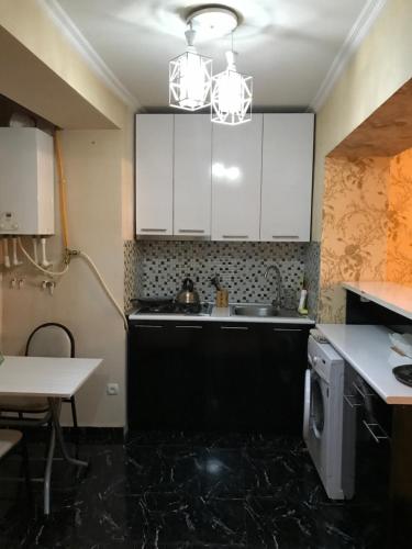 eine Küche mit weißen Schränken, einer Spüle und einer Mikrowelle in der Unterkunft Homee in Tbilisi City