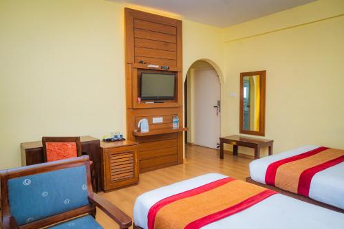 una camera d'albergo con due letti e una televisione di Hotel Crown Himalayas a Pokhara