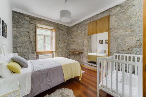 una camera da letto con culla e parete in pietra di Quinta das Fontes - Alojamento Rústico Local e Turismo Rural a São Pedro do Sul