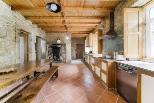 a large kitchen with wooden ceilings and a wooden table at Quinta das Fontes - Alojamento Rústico Local e Turismo Rural in São Pedro do Sul