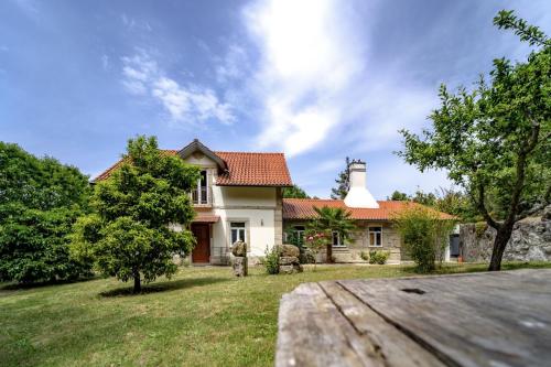 a white house with a chimney on top of a yard at Quinta das Fontes - Alojamento Rústico Local e Turismo Rural in São Pedro do Sul