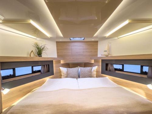 een slaapkamer met een groot wit bed en ramen bij Motoryacht-Futura-Urlaub-im-Yachthafen in Burgtiefe auf Fehmarn 