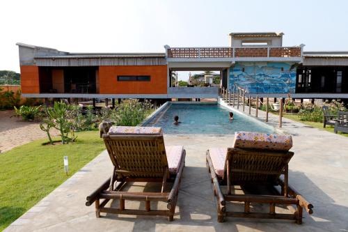 2 Stühle auf einer Terrasse mit Pool in der Unterkunft La Maison Bleue Lome in Lomé