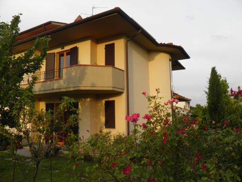 una casa gialla con balcone e alcuni fiori di Casa Roberta a Cavriglia