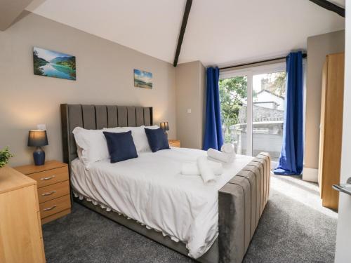 1 dormitorio con 1 cama con cortinas azules y ventana en Clarence House en Dalton in Furness