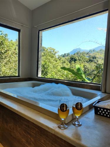 a bath tub with two glasses of wine on a table at Pousada Valle dos Pássaros in Penedo