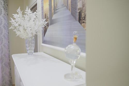 a white table with a vase of flowers and a window at Venere apartement house in Montalto Uffugo