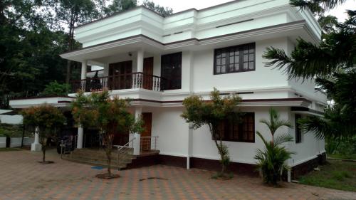 une maison blanche avec des arbres devant elle dans l'établissement Maydale homes, à Kottayam