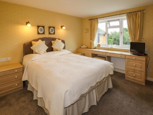 a bedroom with a bed and a desk and a window at Tregarthens in Church Stretton