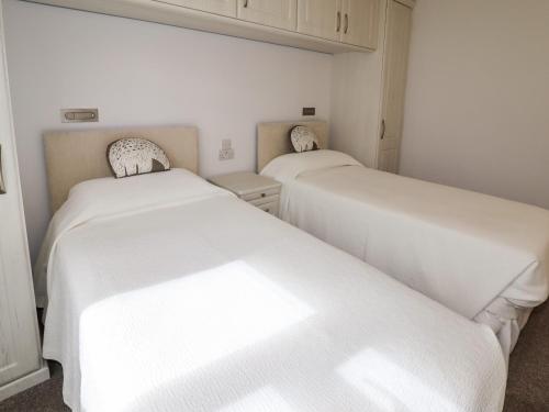 two beds in a room with white sheets at Tregarthens in Church Stretton