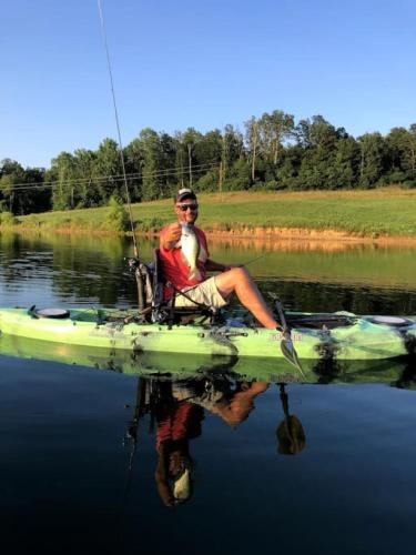 a man sitting in a chair on a kayak in the water at Mammoth Cave Cabin Rentals 7 in Cub Run