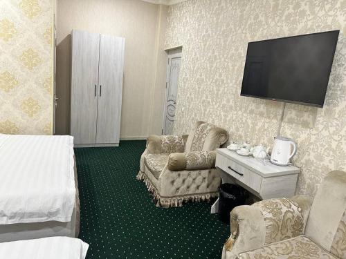 um quarto de hotel com uma cama e uma televisão de ecrã plano em SEMURG HOTEL em Tashkent