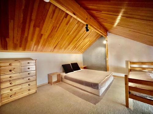 une chambre avec un lit et un plafond en bois dans l'établissement VAUJANYLOCATIONS - LA FARE 30, à Vaujany