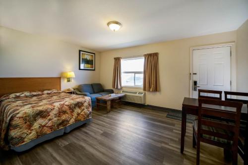 a hotel room with a bed and a desk at Canadas Best Value Inn Fort St John in Fort Saint John