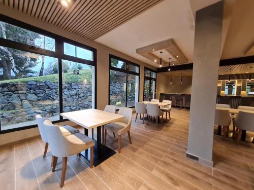 un comedor con mesas, sillas y ventanas en Hotel Alun Nehuen en San Carlos de Bariloche