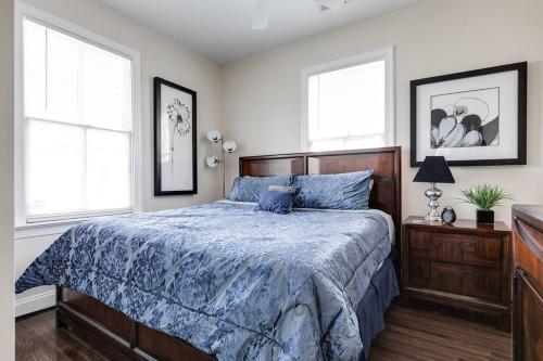 1 Schlafzimmer mit einem Bett mit blauer Decke und 2 Fenstern in der Unterkunft Modern, Convenient Gem: Urban Retreat 'n Richmond in Richmond