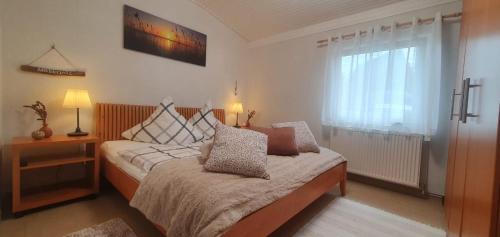 a bedroom with a bed with pillows and a window at Ferienhaus Frische Brise direkt am Nordsee Deich in Spieka-Neufeld
