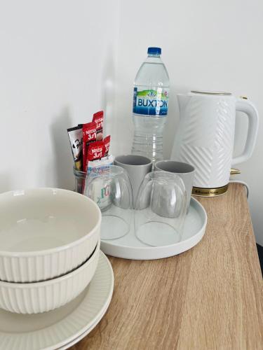 einen Tisch mit Teller und Tassen und eine Flasche Wasser in der Unterkunft Simple Stay-Double Room Escape with Modern Luxury in Portchester