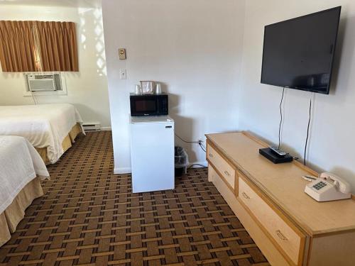 a hotel room with a bed and a flat screen tv at Ski's Western Motel in Great Falls
