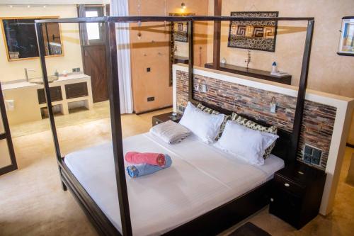 a bedroom with a four poster bed and a brick wall at La Maison Bleue Lome in Lomé