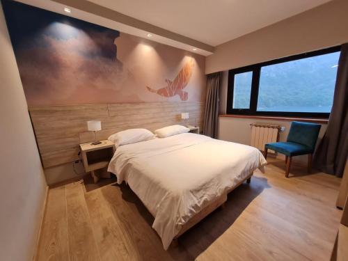sypialnia z dużym łóżkiem i niebieskim krzesłem w obiekcie Hotel Alun Nehuen w mieście Bariloche
