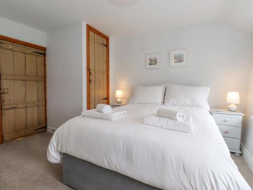 a bedroom with a large white bed with two towels at Squirrel Cottage in Keswick