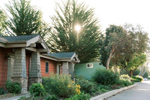 a house with the sun shining through the trees at Cambria Pines Lodge in Cambria
