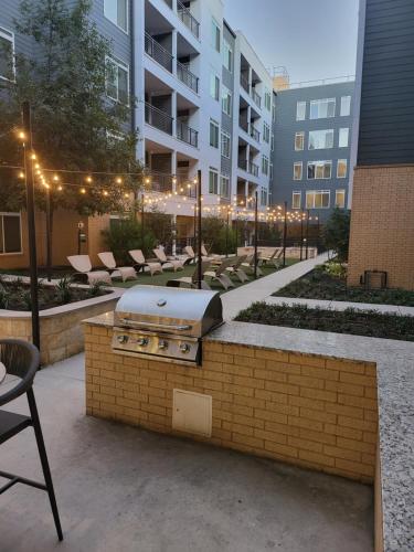 a grill in a courtyard with chairs and a building at Beautiful Condo on Riverwalk w King Ste Free Parking Pet friendly centrally Located on the Riverwalk in San Antonio