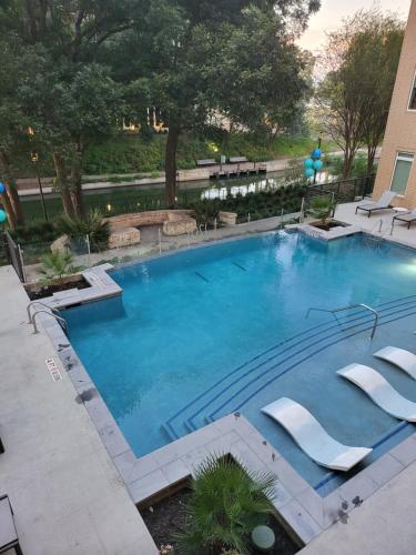 a large swimming pool with lounge chairs around it at Beautiful Condo on Riverwalk w King Ste Free Parking Pet friendly centrally Located on the Riverwalk in San Antonio