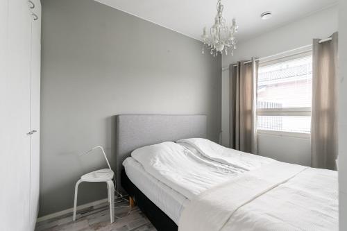 a white bedroom with a bed and a chandelier at Vitosjussi in Hämeenlinna