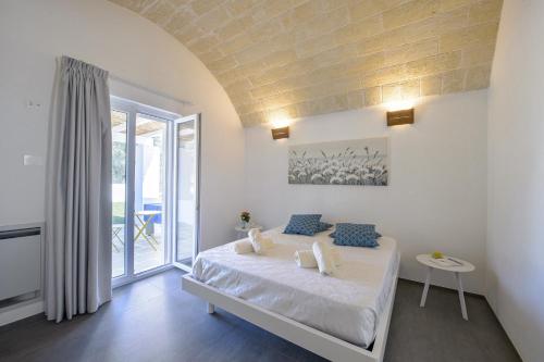ein weißes Schlafzimmer mit einem Bett und einem Balkon in der Unterkunft Villa Alice by Villa Plus in San Michele Salentino