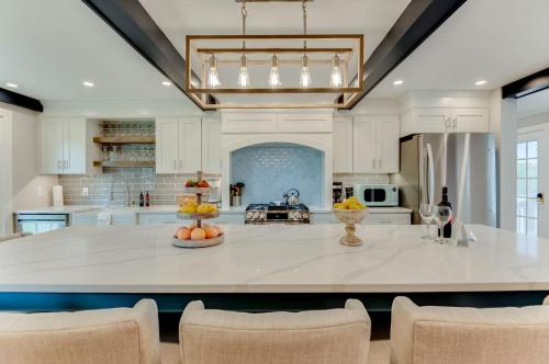 uma grande cozinha com uma grande ilha branca com cadeiras em The Guest House - Estate em Excelsior